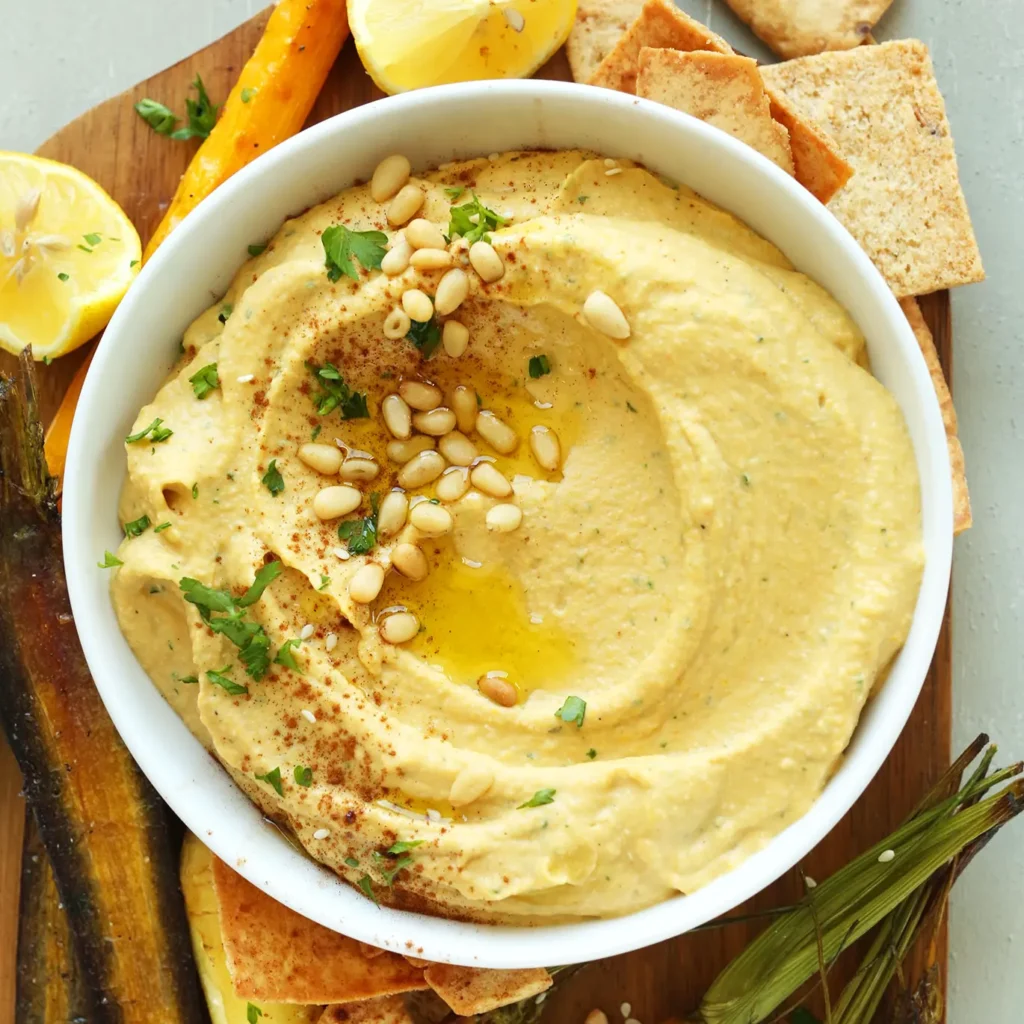 Butternut squash hummus image on a white plate, surounded by crackers.