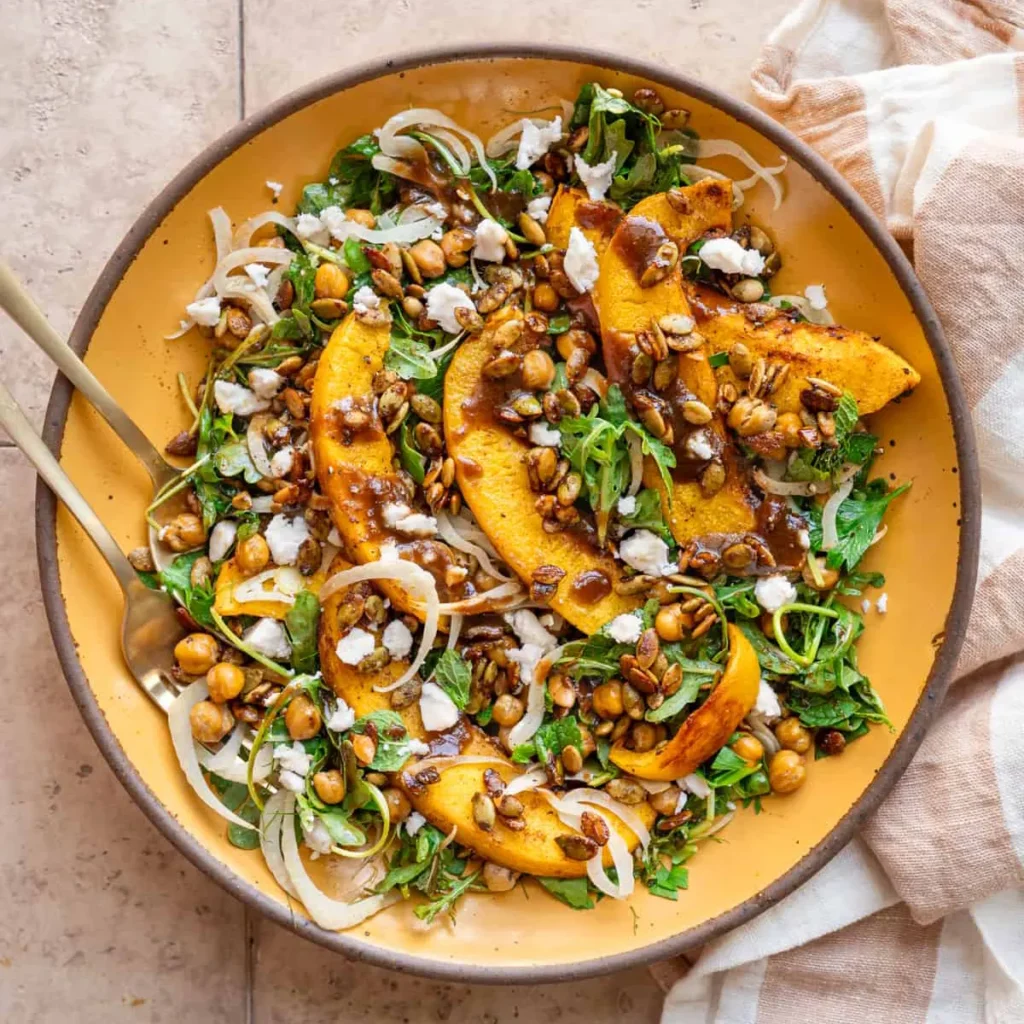 A plate with roasted pumpkin salad, topped with vegan feta.